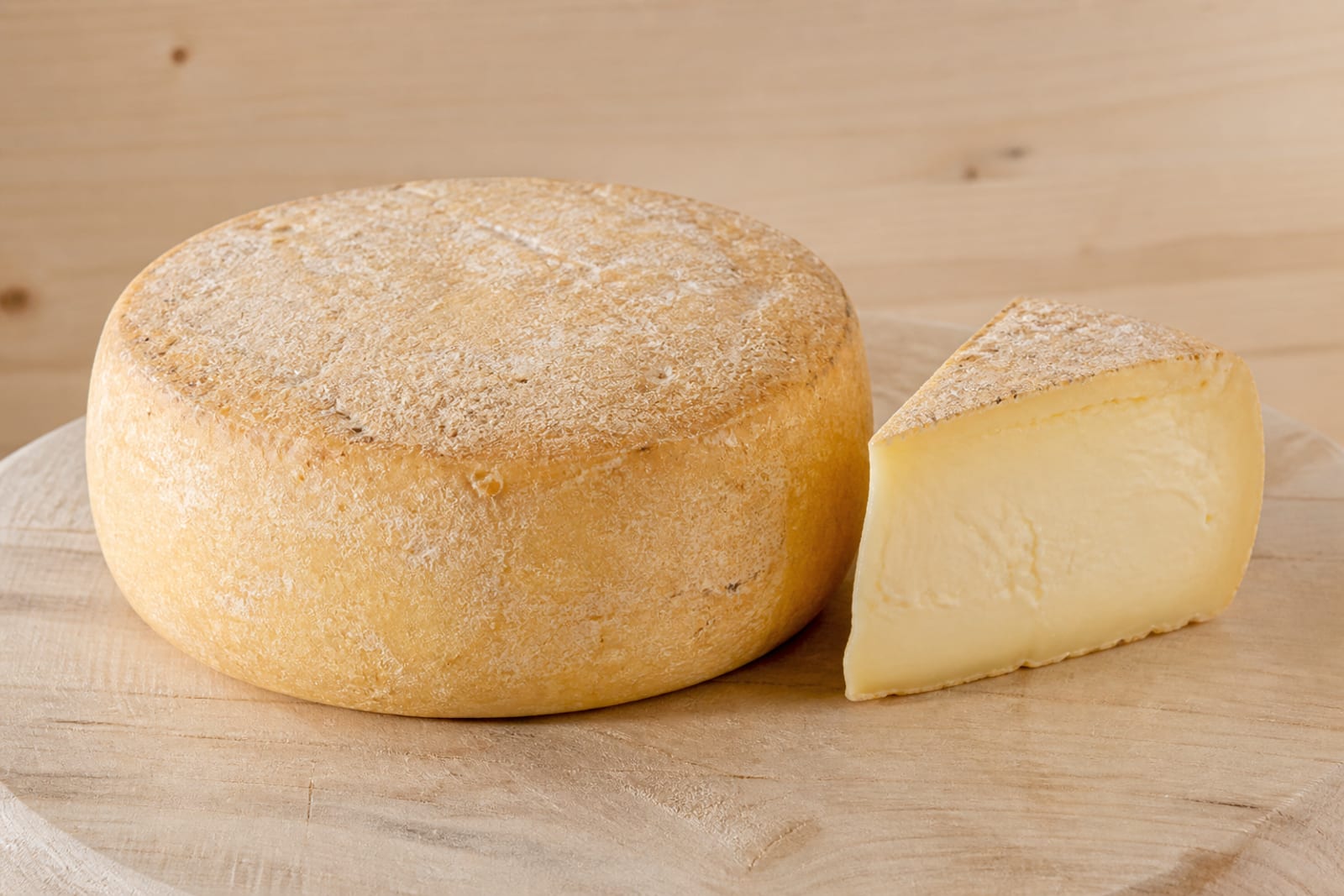 Laib Glundner Käse auf einem Holzbrett neben einem Küchentuch
