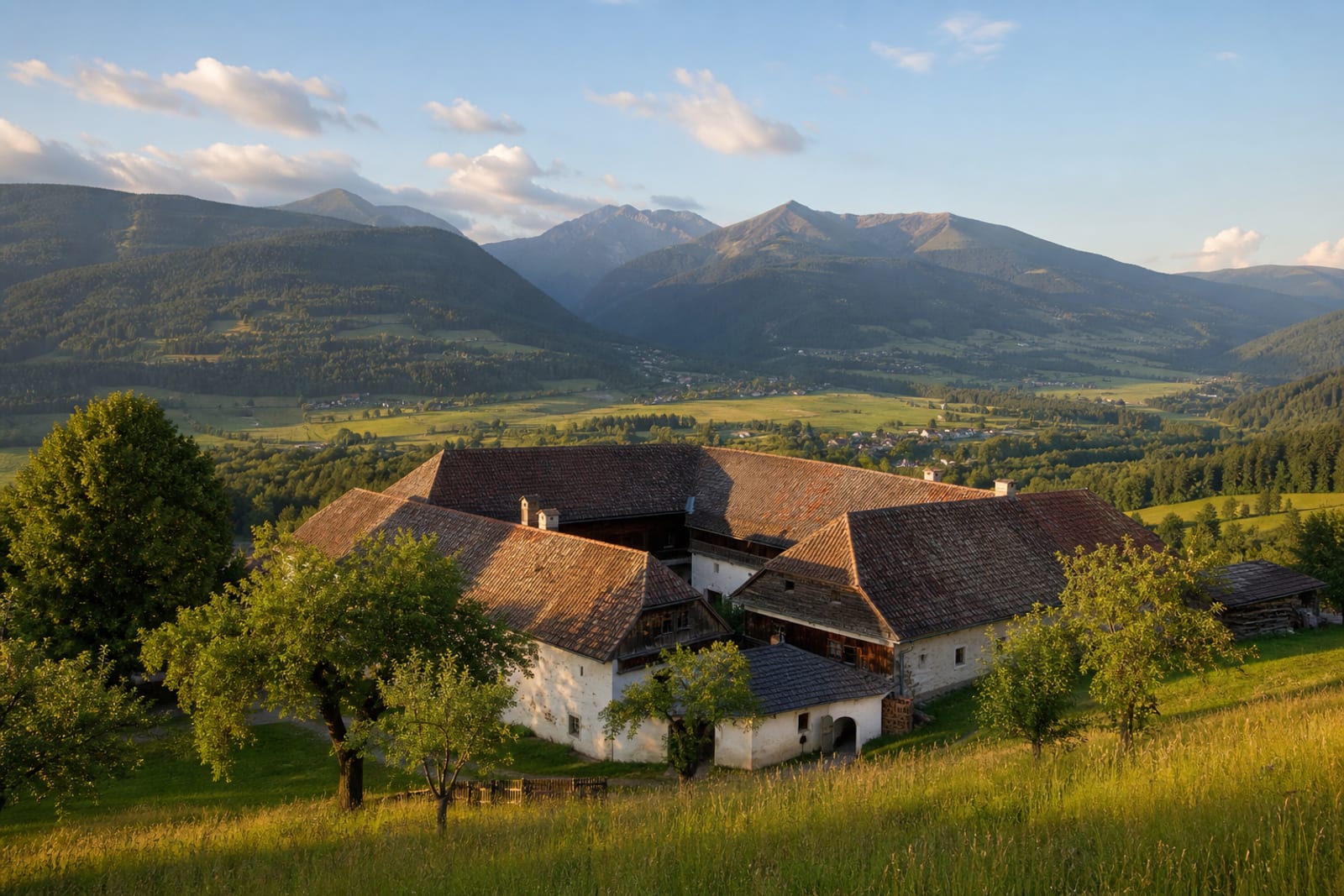 Der Lärchmoserhof auf einer Wiesenterrasse über dem Gurktal, dahinter die Nockberge im Abendlicht